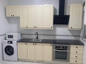 a kitchen with white cabinets and a sink and a dishwasher at Chalet a 2 metros de la playa in Rota +9 photos