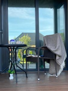 a patio with a table and a chair and a table and a window at Vila Naktižiedė in Šventoji