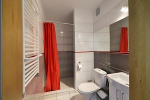 a bathroom with a toilet and a red shower curtain at Złota 24 in Karwia +32 photos