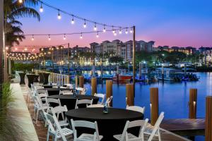 a restaurant with tables and chairs and a marina at Hyatt House Naples 5th Avenue in Naples