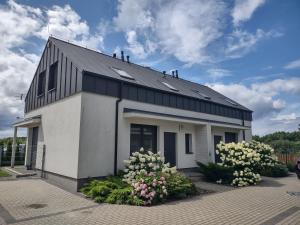 a white and black building with flowers in front of it at Villa Anna in Międzywodzie