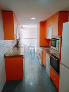 a kitchen with orange cabinets and a table in it at Apartamento Monet Playa in Rincón de la Victoria