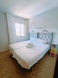 a bedroom with a bed with white sheets and a window at Apartamento Monet Playa in Rincón de la Victoria