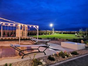 a patio with a table and benches at night at Domki Hulaj Dusza in Bobolin