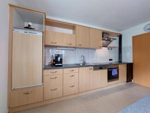 a kitchen with wooden cabinets and a sink at Landhaus Irena - Familienfreundliches Ferienhaus an der Zillerpromenade mit Bergblick in Ramsau im Zillertal +13 photos