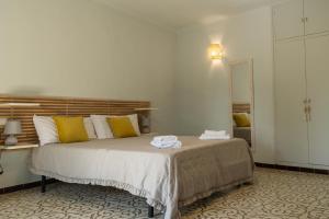 a bedroom with a bed with yellow and white pillows at Can Paulí in Ultramort