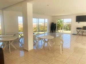 a dining room with tables and chairs and windows at Appart Tanger Beach in Tangier