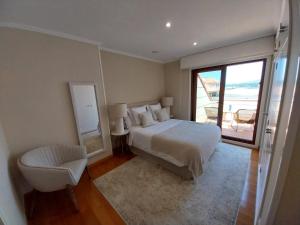 a bedroom with a bed and a chair and a window at PISO DÚPLEX - ISLA DE LA TOJA (O GROVE) in O Grove +56 photos
