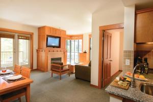 a kitchen and living room with a couch and a television at Pan Pacific Whistler Mountainside in Whistler