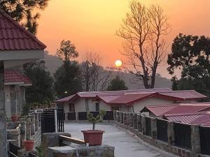 a sun setting over a row of houses with a potted plant at Vista Casita Ranikhet Serene Homestay Himalaya Lap in Rānīkhet