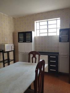 eine Küche mit einem Tisch, 2 Stühlen und einem Fenster in der Unterkunft Casa de Vó in Campina Grande