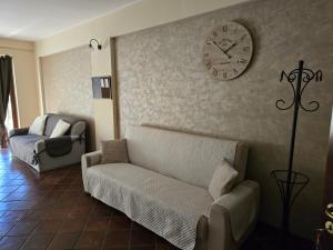 a living room with a couch and a clock on the wall at Casa La Ferula apt1 vicino al mare e Taormina in SantʼAlessio Siculo