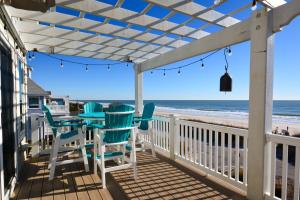 eine Terrasse mit Stühlen, einem Tisch und dem Strand in der Unterkunft Sweet M'Ocean in Thomas Landing