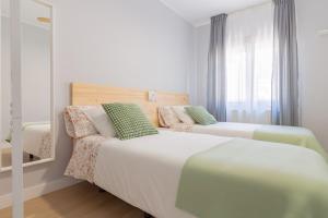 two beds in a small bedroom with a window at AH Apartamento Urban Lena VUT6048AS in Pola de Lena
