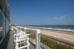 een balkon met witte stoelen met uitzicht op het strand bij Geaux Big in North Topsail Beach