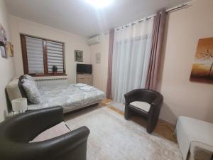 a small bedroom with a bed and a chair at Apartman Bojana in Vrnjačka Banja