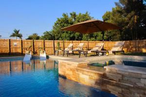 a pool with chairs and an umbrella in the water at Fox Garden-heated Pool-spa- Boho-downtown & Beach in Fort Lauderdale