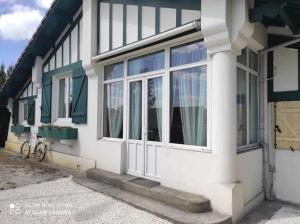 a white house with windows and a bike parked outside at La belle basco landaise in Mimizan