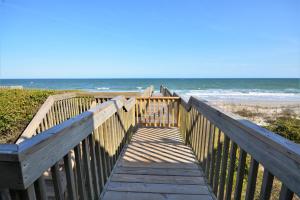 een houten promenade die leidt naar een strand met de oceaan bij 4 By The Shore in Watts Landing