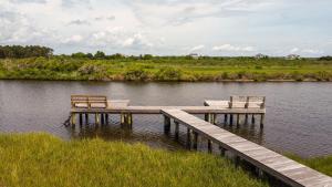 two benches sitting on a dock in a body of water at Beyond the Sea in Thomas Landing