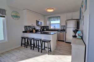 a kitchen with white cabinets and black counter stools at On Slow Time in West Onslow Beach