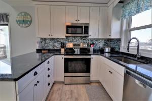 a kitchen with white cabinets and stainless steel appliances at On Slow Time in West Onslow Beach
