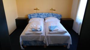 1 cama con 2 almohadas y toallas en Hotel CB Royal, en České Budějovice