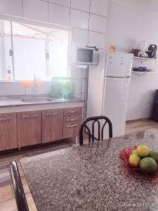 eine Küche mit einem Tisch und einem weißen Kühlschrank in der Unterkunft casa da Dora próx da praia in Caraguatatuba