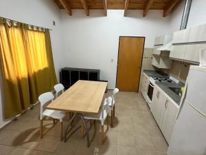 a kitchen with a wooden table and white appliances at Refugio Andino 2 in Malargüe