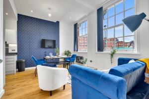 Una sala de estar con un sofá azul y sillas. en Sloane House, en Birmingham
