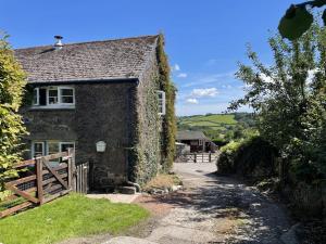 an old stone house with a gate and a driveway at The Cottage in Ashburton