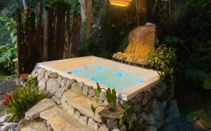 a hot tub in a stone wall in a garden at Chapola Home in Guarne