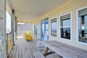 a porch with a wooden bench and a table at Just Chill'n in North Topsail Beach