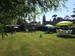 a yard with two umbrellas and tables and chairs at La Maison Genevier - Chambre Doréline in Montreuil-en-Touraine +4 photos