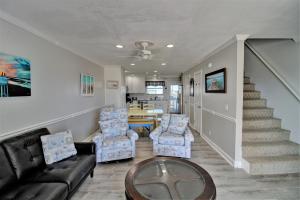 a living room with a couch and chairs and a staircase at Living on the Edge Too in North Topsail Beach