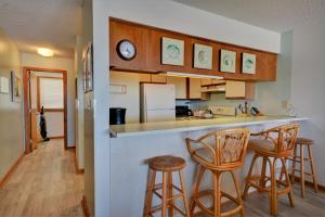 une cuisine avec trois tabourets de bar et un comptoir dans l'établissement Queens Grant B-106, à Topsail Beach