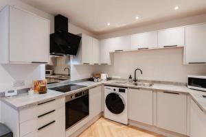 a white kitchen with white cabinets and a dishwasher at Boutique Apartment - MazeryStays in Exley
