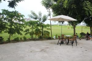 Hotel Kien Nga في Thach Loi: طاولة وكراسي مع مظلة في الحديقة