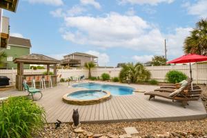 einen Hinterhof mit einem Pool und einer Terrasse mit Stühlen und einem Sonnenschirm in der Unterkunft Shore Blessed in North Topsail Beach