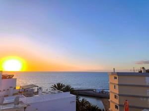 a sunset over the ocean from a building at Deluxe Arguineguin Beach in Arguineguín +33 photos