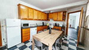 a kitchen with a wooden table and a white refrigerator at Casa Azul (Blue House) in Urzelina