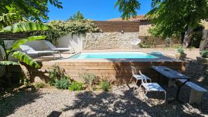 a swimming pool in a yard with two chairs and a table at Chez Lola-Maison d'hôtes Corbières in Durban-Corbières