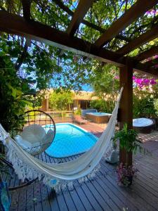 a hammock on a deck next to a pool at Pousada da Praia in Garopaba