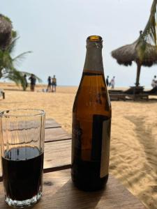 una bottiglia di birra seduta su un tavolo accanto a un bicchiere di Villa tropical a Kribi