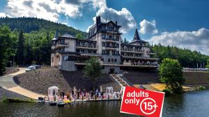 a large building with a sign in front of it at Retro Riverside Wellness Resort in Karlovy Vary