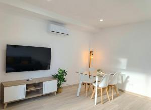 a living room with a table and a flat screen tv at Deluxe Arguineguin Beach in Arguineguín