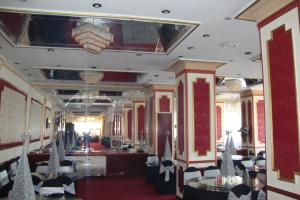 uma sala de jantar com mesas e cadeiras e um lustre em Asafra Hotel Apartments Egyptian only price em Alexandria