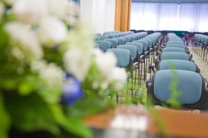una fila de sillas azules en una habitación con flores en San Gabriele, en Loreto