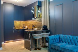 a kitchen with blue walls and a bar with a blue couch at Golden Park Aparthotel in Szczecin