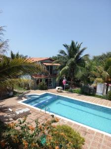 a pool in front of a house with palm trees at Hostal las Cabañas Santa Veronica in Santa Veronica